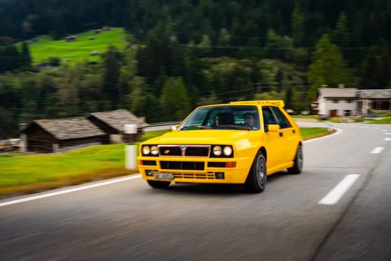 Gelber Lancia Delta Integrale auf einer Ausfahrt durch die Berge