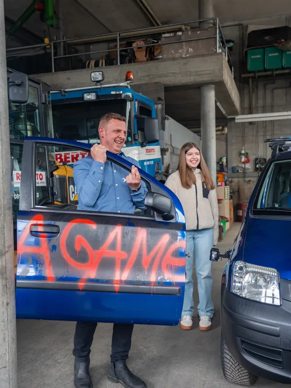 Panda-Games-Team in einer Werkstatt, ein Fahrer hält eine mit «Game» besprayte Autotür