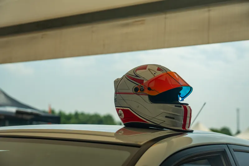 Rennhelm liegt auf dem Dach eines Autos an der Rennstrecke