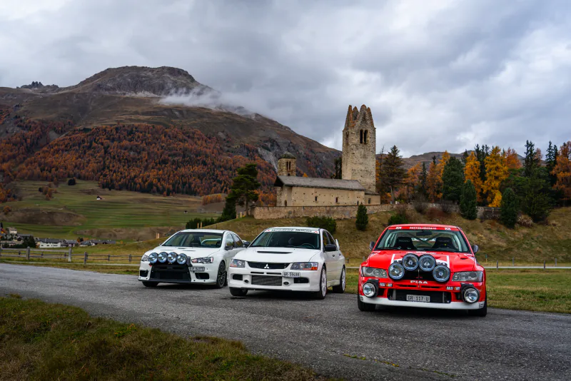 Mitsubishi Evos vor Kirche und Herbstlärchen im Engadin
