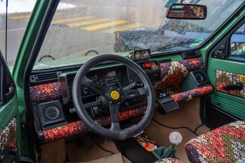 Innenraum eines grünen Fiat Panda mit buntem Strickbezug und Sportlenkrad