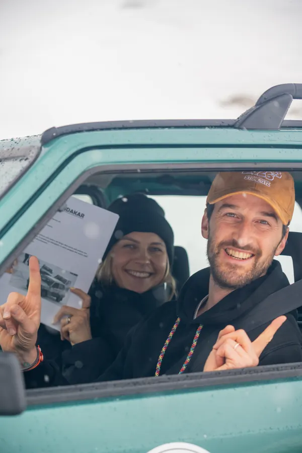 Fahrerin und Fahrer lachen aus dem Fenster ihres türkisfarbenen Pandas
