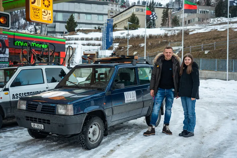 Zwei Teilnehmende posieren neben ihrem Fiat Panda auf einem verschneiten Platz