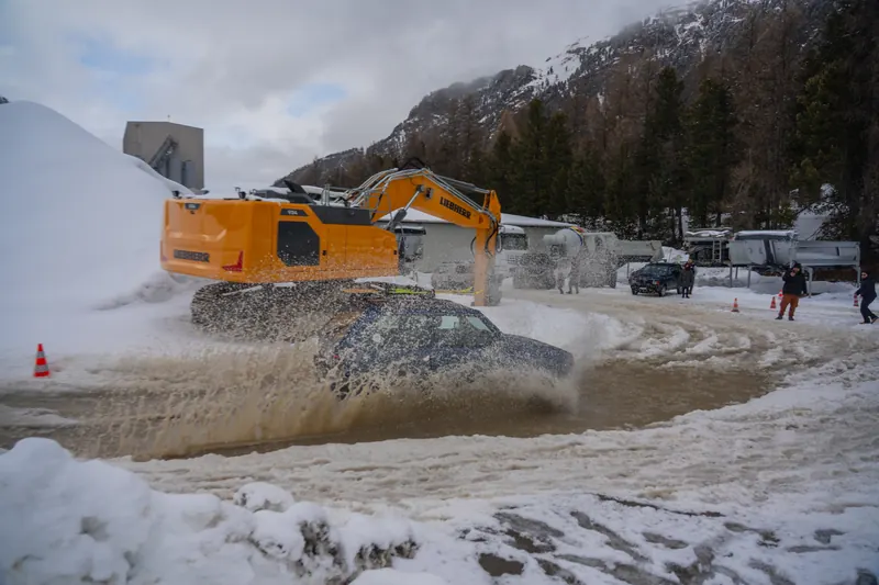 Fiat Panda driftet durch Schneematsch, im Hintergrund ein Bagger und verschneite Berge
